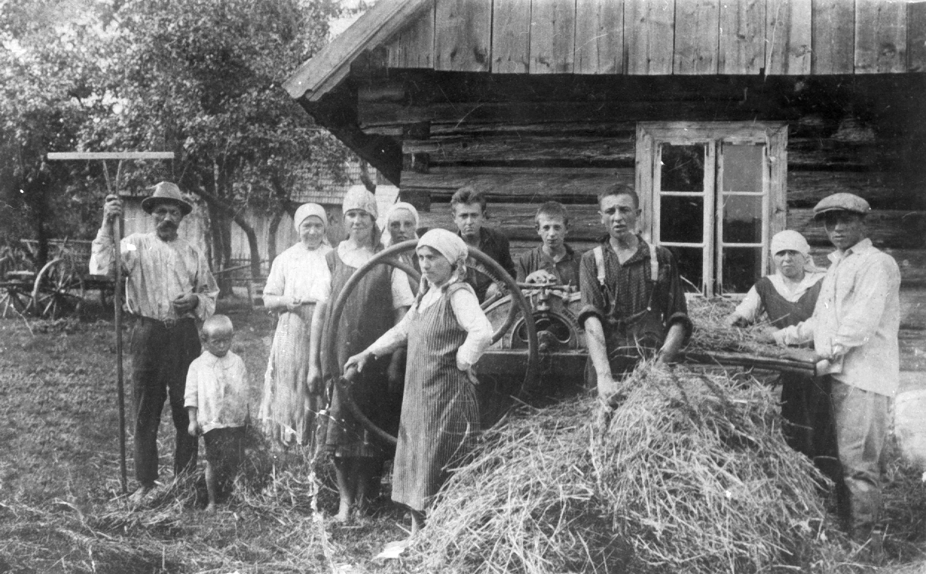 Rok i miejsce wykonania: 1924 r., Odrzykoń, gm. Wojaszówka, pow. krośnieński, woj. podkarpackie.

Fotografia przedstawia grupę ludzi w różnym wieku, w tym dzieci, przy dużej, ręcznej młocarni, obok której leży zżęte zboże. Najstarszy z mężczyzn trzyma grabie na sztorc. Obok niego stoi chłopiec w wieku około trzech lat. Wszyscy ubrani są w zwykłe codzienne stroje. Kobiety na głowach mają jasne chustki zawiązane z tyłu. Zdjęcie wykonano na tle ściany szczytowej domu, zbudowanego w konstrukcji zrębowej. Z lewej strony zdjęcia widać podwórko, wóz drabiniasty, drewniane zabudowania gospodarcze i sad. Według nadawcy zdjęcia była to pierwsza młocarnia ręczna w Odrzykoniu.

Autor zdjęcia: nieznany.

Zdjęcie ze zbiorów prywatnych, nadesłał Jan Guzek z Sycowej Huty, pow. kościerski, woj. pomorskie.

Nr kat. 90-20