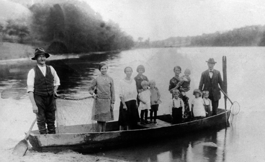 Rok i miejsce wykonania: ok. 1930 r., jezioro Byszewskie, Byszewo, gm. Koronowo, pow. bydgoski, woj. kujawsko-pomorskie.

Fotografia przedstawia grupę ludzi stojących w łodzi na jeziorze. Z lewej strony widać mężczyznę w białej koszuli z podwiniętymi rękawami, w kamizelce i kapeluszu. W jednej ręce trzyma sieć, od drugiej strony podtrzymywaną przez młodą kobietę. Prócz nich w łodzi stoją trzy inne kobiety, odświętnie ubrane, sześcioro małych dzieci oraz mężczyzna w garniturze i kapeluszu, trzymający siatkę na ryby. W tle widać jezioro otoczone przez las. Według nadawcy zdjęcia przedstawia ono rodzinę rybacką przy pracy. Po lewej stronie fotografii stoi dziadek nadawcy, będący mistrzem rybackim, Bogusław Płotka (nomen omen).

Zdjęcie zostało wykonane przez Leona Lemańskiego, wuja właściciela fotografii, nad jeziorem Byszewskim koło Koronowa.

Autor zdjęcia: Leon Lemański.

Zdjęcie ze zbiorów prywatnych rodziny Płotka i Lemańskich.

Nr kat. 107-1