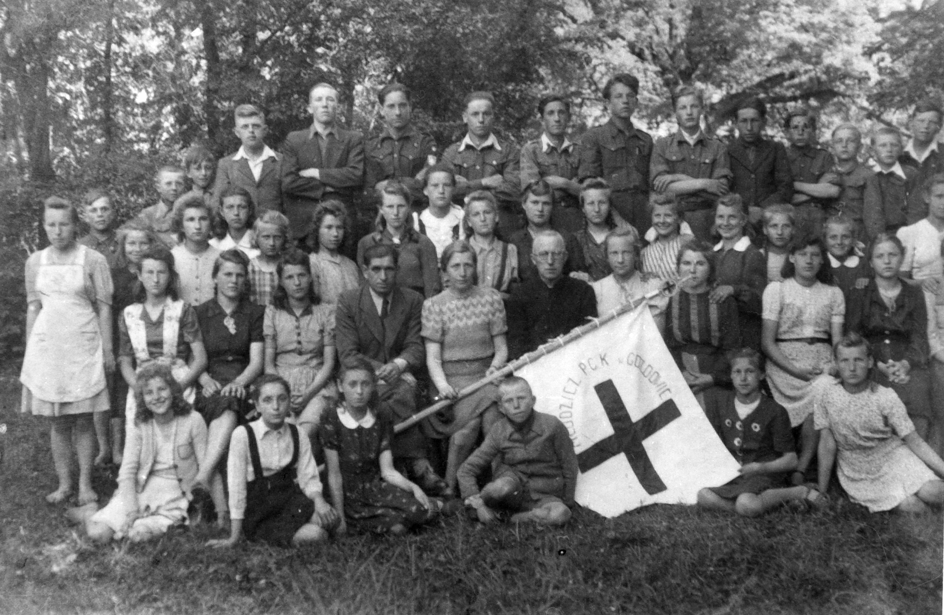 Rok i miejsce wykonania: 1947 r., Gozdowo, gm. Gozdowo, pow. sierpecki, woj. Mazowieckie.

Zdjęcie przedstawia członków Polskiego Czerwonego Krzyża zrzeszonych przy szkole podstawowej w Gozdowie. Jest to duża grupa młodzieży żeńskiej i męskiej. Pomiędzy młodzieżą siedzi troje nauczycieli: dwóch mężczyzn i kobieta, która trzyma sztandar. Na nim widoczny równoramienny krzyż i napis: „Młodzież PCK w Gozdowie”.

Autor zdjęcia: nieznany.

Zdjęcie ze zbiorów prywatnych, nadesłał: Sławomir Ruta z Zawad, pow. tomaszowski, woj. łódzkie.

Nr kat. 76-20