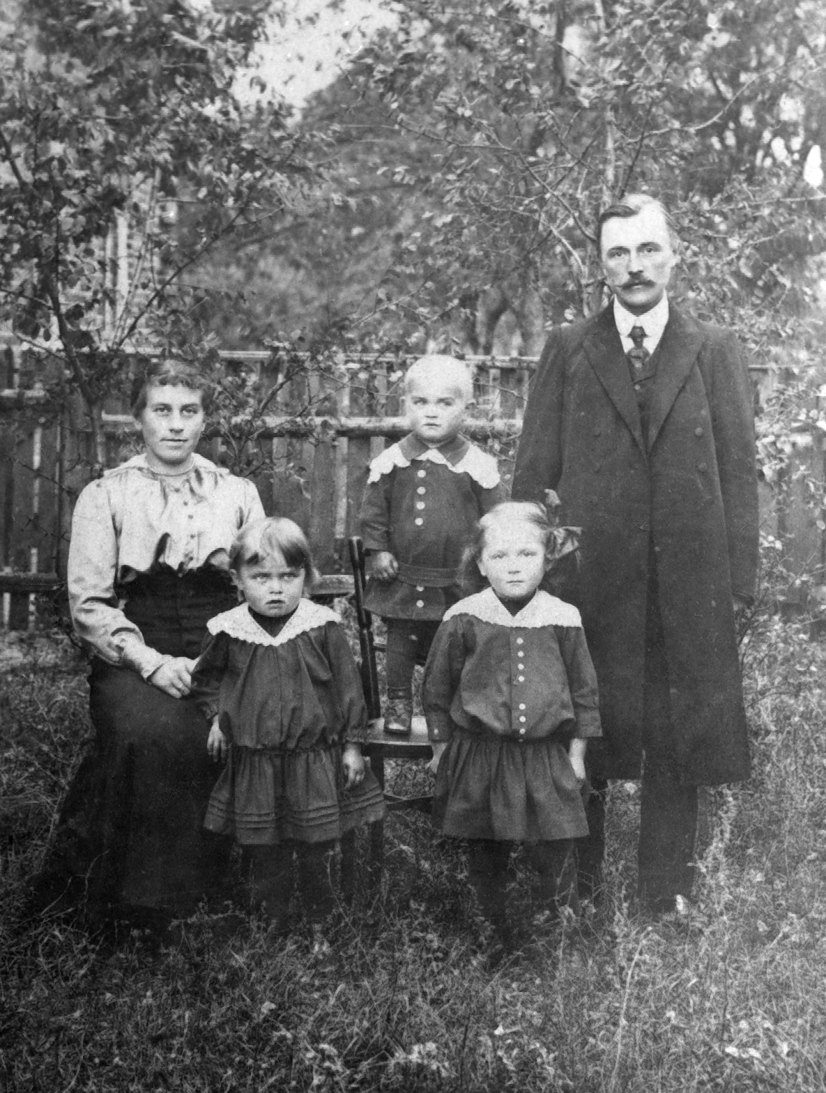 Rok i miejsce wykonania: 1921 r., wieś Starce, gm. Brąszewice, pow. sieradzki, woj. łódzkie.

Fotografia przedstawia małżeństwo z trójką małych dzieci – dwiema starszymi dziewczynkami i najmłodszym chłopcem. Wszyscy są odświętnie ubrani. Fotografia została wykonana w bujnym przydomowym ogrodzie. W tle widoczny sad.

Według relacji nadawcy zdjęcia przedstawia ono rodzinę J. i B. Bilskich z dziećmi. Pan B. był nauczycielem w szkole w Starcach.

Zdjęcie zostało wykonane w wsi Starce przez fotografa p. Zająca ze Złoczewa w pow. sieradzkim.

Zdjęcie ze zbiorów prywatnych rodziny Jarczewskich.

Nr kat. 64-16