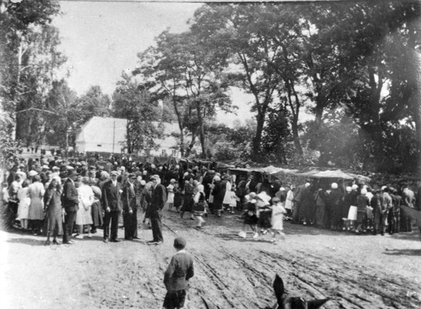 Rok i miejsce wykonania: 26.07.1932 r., Puszcza Mariańska, gm. Puszcza Mariańska, pow. żyrardowski, woj. mazowieckie.

Fotografia przedstawia tłum ludzi przy straganach handlowych, ustawionych przy okazji odpustu w dzień św. Anny. Widać na niej dorosłych oraz dzieci w odświętnych strojach.

Na odwrocie zdjęcia napis: „Zdjęcie wykonane w dniu 26 lipca 1932 roku podczas odpustu na św. Annę w Puszczy Mariańskiej z widokiem na budynek gminy. Wykonane przez B. Kieresińskiego, miejscowego organistę w Puszczy Mariańskiej, b. gminie Korabiewice, w b. powiecie skierniewickim”.

Autor zdjęcia: B. Kieresiński, miejscowy organista w Puszczy Mariańskiej.

Zdjęcie ze zbiorów prywatnych, nadesłał: Władysław Szczęśniak z Łodzi.

Nr kat. 20-3