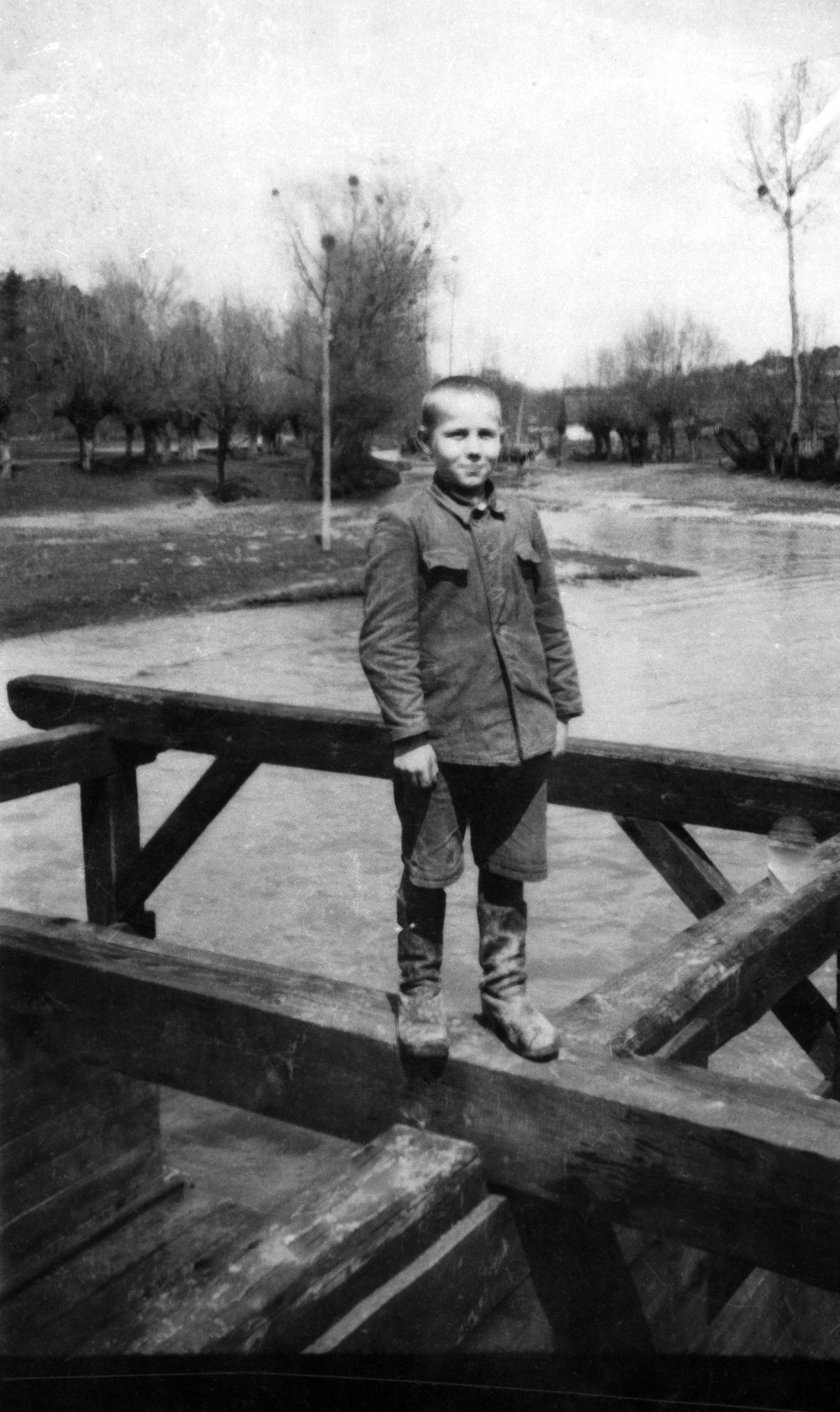 Rok i miejsce wykonania: wczesna wiosna 1930 r., Blinów (Roztocze Zachodnie), gm. Szastarka, pow. kraśnicki, woj. lubelskie.

Fotografia przedstawia nastoletniego chłopca, który stoi na konstrukcji z drewnianych bali nad szeroką rzeką, wezbraną roztopami. Widziane gdzieniegdzie resztki leżącego śniegu oraz surowy krajobraz wskazują, że zdjęcie wykonano na przedwiośniu. Chłopiec ma krótko ścięte włosy, ubrany jest w kurtkę mundurową zapinaną na guziki (z kołnierzykiem i symetrycznymi kieszeniami na piersi) oraz spodnie do kolan. Na nogach ma wysokie, przyduże, zniszczone buty.

Z informacji dołączonych przez nadawczynię zdjęcia wynika, że przedstawia ono syna jej babci, Zygmunta Kawałę, który zginął w czasie wojny.

Autor zdjęcia: nieznany.

Zdjęcie ze zbiorów prywatnych, nadesłała: brak danych. Nr kat. 261-3