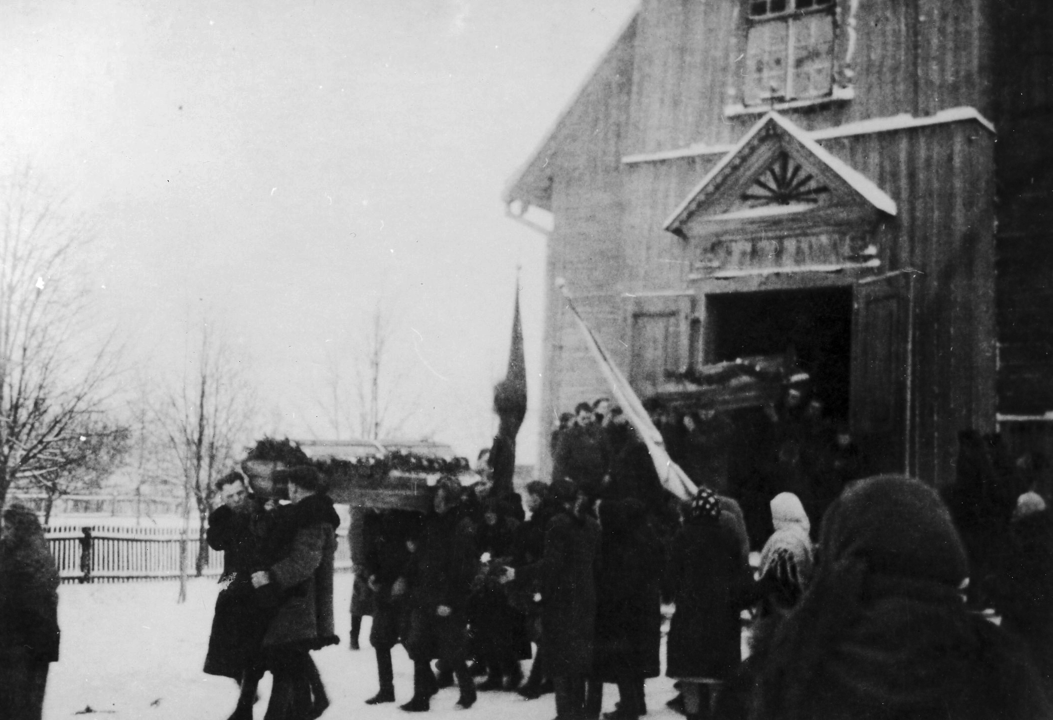 Rok i miejsce wykonania: 1943 r., Kłodnica Górna, gm. Borzechów, pow. lubelski, woj. lubelskie.

Fotografia przedstawia drewniany kościół oraz ludzi, którzy wynoszą na swoich ramionach trumny udekorowane wieńcami. Wokół nich gromadzi się społeczność wiejska w zimowej odzieży. Trwa podczas śnieżyca. Według informacji podanych przez nadawczynię zdjęcia dokumentuje ono uroczystości pogrzebowe trójki kilkunastoletnich dzieci, które zginęły w Kłodnicy uciekając przed Niemcami. Byli to: Stefan Wąsik, Bogumiła Woźniacka, Janina Wąsik. Zdjęcie to, podobnie jak poprzednie, jest jednym z kilku, które dokumentują to tragiczne wydarzenie.

Autor zdjęcia: nieznany.

Zdjęcie ze zbiorów prywatnych, nadesłała: Elżbieta Filipek z Lublina, woj. lubelskie.

Nr kat. 231-19