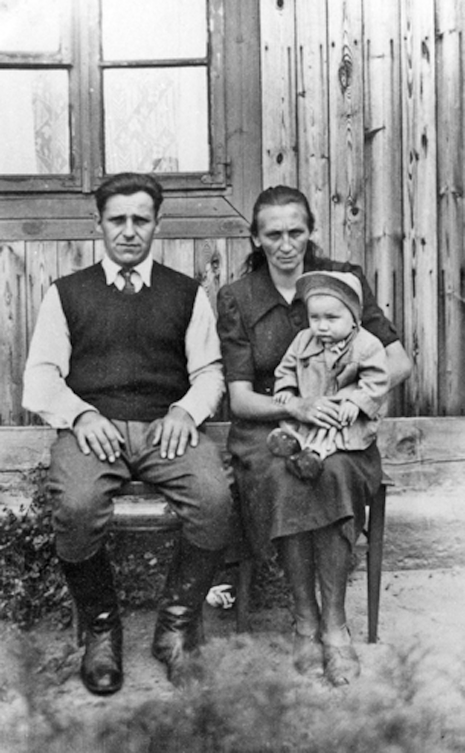 Rok i miejsce wykonania: czerwiec 1947 r., Łyse, gm. Łyse, pow. ostrołęcki, woj. mazowiecki.

Fotografia przedstawia mężczyznę i kobietę, którzy siedzą na ławce przed drewnianym domem, trzymając na kolanach około roczne dziecko. Mężczyzna ubrany jest w białą koszulę, ciemną kamizelkę i bryczesy, a kobieta w ciemną sukienkę. Dziecko (o trudnej do określenia płci) ma na sobie płaszczyk i kaszkiet. Według nadawczyni zdjęcia przedstawia ono małżeństwo Eleonorę i Konstantego Olender z dzieckiem.

Autor zdjęcia: Władysław Sokołowski ze wsi Łyse.

Zdjęcie ze zbiorów prywatnych, nadesłała: Irena Mossakowska ze Szczytna, pow. szczycieński, woj. warmińsko-mazurskie.

Nr kat. 224-18