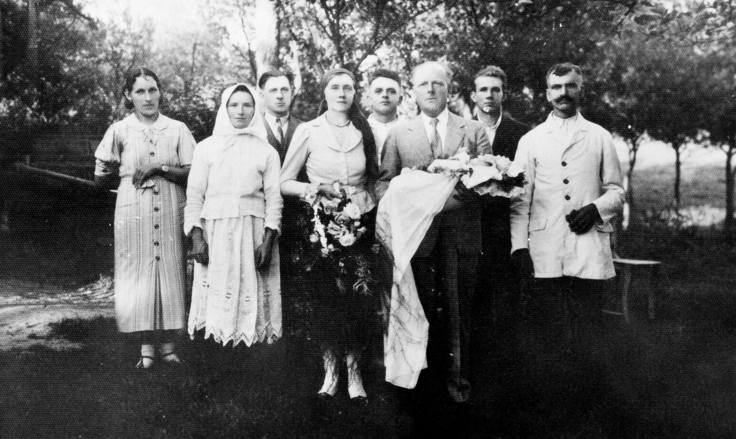 Rok i miejsce wykonania: 1935 r., Handzlówka, gm. Łańcut, pow. łańcucki, woj. podkarpackie.

Fotografia upamiętnia chrzest dziecka i została wykonana w plenerze, na tle dużych drzew. Według nadawczyni zdjęcia przedstawia ono chrzest Andrzeja Kuźniara, siódmego syna Józefa Kuźniara z Handzlówki. Rodzicami chrzestnymi są Julia z Wojnarów Magrysiowa i Prezydent Rzeczpospolitej Polskiej Ignacy Mościcki. W imieniu Prezydenta dziecko do chrztu trzyma Alfred hrabia Potocki z Łańcuta. Na zdjęciu widoczni są: hrabia Potocki, który trzyma biały becik, obok niego (z prawej strony) ojciec dziecka, a z lewej matka. Pierwsza kobieta widoczna po lewej stronie fotografii to akuszerka Józefa Morawska. Więcej na ten temat można przeczytać w artykule, którego fragment zamieszczamy poniżej: „Prezydenckim dekretem w 1926 r. [Prezydent Ignacy Mościcki] postanowił, y każdy siódmy syn w rodzinie (również bliźniacy) stawał się jego chrześniakiem po wcześniejszym ustaleniu w środowisku, że »rodzina jest praworządna, uczciwa, cnotliwa i szlachetna«.

Spośród siódmych synów Mościcki dla 911 stał się ojcem chrzestnym (462 odmówiono tego przywileju). Zapewniono im na owe czasy znaczne preferencje. Obowiązek nauki szkolnej dotyczył wówczas dzieci i młodzieży do lat czternastu. Prezydenckim synom chrzestnym państwo zagwarantowało jednak możliwość dalszej bezpłatnej nauki – w tym studiów – również poza Polską. Zwolniono ich ponadto z kosztów leczenia, a przejazdy publicznymi środkami komunikacji były darmowe także dla najbliższej rodziny.

Wśród bardziej wymiernych profitów było ufundowanie tzw. czerwonej książeczki PKO z wkładem początkowym w wysokości 50 zł i gwarantowanymi odsetkami 6 proc. rocznie. Była to mniej więcej wartość krowy, ale pieniędzy nie można było podjąć do ukończenia 18. roku życia.

Przed wojną normą były rodziny wielodzietne, mimo to siódmy syn – córek nie liczono! – był rzadkością. Prezydent Mościcki rzadko osobiście trzymał dzieci do chrztu. W jego zastępstwie najczęściej robił to minister, czasem starosta lub wójt, ewentualnie sekretarz gminy. W księgach parafialnych występował jednak zawsze wpis, że ojcem chrzestnym jest prezydent Ignacy Mościcki”, (Prezydenccy chrześniacy,18.06.2024)

Autor zdjęcia: nieznany.

Zdjęcie ze zbiorów prywatnych, nadesłała: Maria Magryś z Rzeszowa, woj. podkarpackie.

Nr kat. 336-15