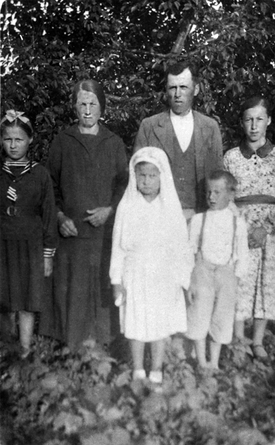 Rok i miejsce wykonania: 29.06.1940 r., brak danych.

Fotografia przedstawia kobietę i mężczyznę z czwórką dzieci (trzy dziewczynki i jeden chłopiec) w różnym wieku, stojących na tle zieleni. Wszyscy są odświętnie ubrani. Pośrodku, na pierwszym planie, widoczna dziewczynka cała w bieli, z welonem na głowie, swobodnie opadając na ramiona. W prawej dłoni trzyma świecę. Prawdopodobnie jest to zdjęcie upamiętniające jej Pierwszą Komunię Świętą. Na odwrocie zdjęcia napis: „29. Czerwca 1940 r. To zdjęcie zrobione. Robił go Mazurkiewicz ze Stacji Zawada. Michał, Katarzyna Tomaszewskie z dzieciami” (pisownia oryginalna).

Autor zdjęcia: nieznany.

Zdjęcie ze zbiorów prywatnych, nadesłał/nadesłała: brak danych.

Nr kat. 22-18